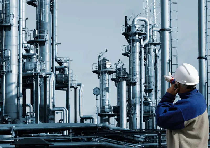 أبراج معالجة في منشأة نفط وغاز ومهندس يرتدي خوذة السلامة يتفقد الموقع