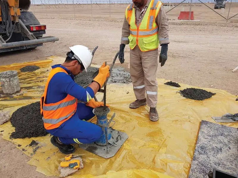 Quality technician testing concrete on site while a supervisor observes